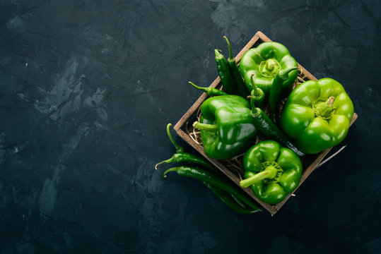 Fresh green pepper and chili pepper in a wooden box. Top view. Free space for text.
