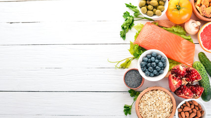 A set of healthy food. Fish, nuts, protein, berries, vegetables and fruits. On a white background. Top view. Free space for text. - obrazy, fototapety, plakaty