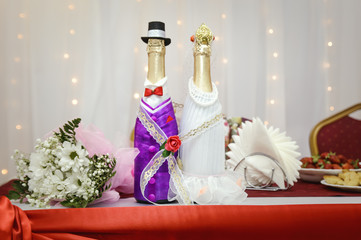 Decorated bottles with champagne are on the festive table. Wedding traditions.