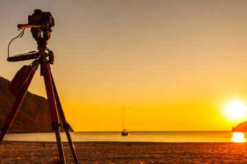 Camera taking picture of sunrise over sea surface