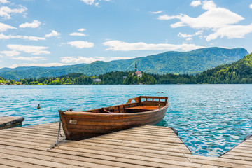 Harbor and boat on the Bled lake, Slovenia. Wooden boats on the pure blue water. Summer day near the Alps and forest
