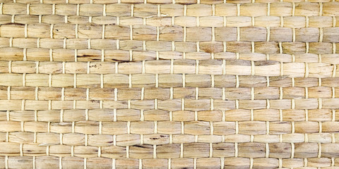 A woven Mat of reeds or straw-yellow in color. The texture of dry cane. Light yellow.