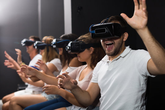 Portrait of young male which is watching exciting movie in VR glasses