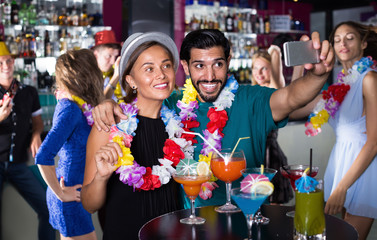 Man with woman making selfie on hawaiian party