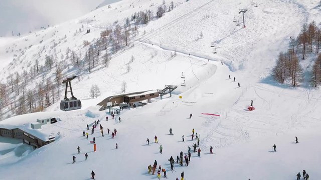 Tourists ice skiing at Chamonix-Mont-Blanc France with a cable car passing by in the corner