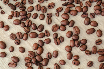 Fresh roasted brown arabica coffee beans spilled on wooden table, background, top view