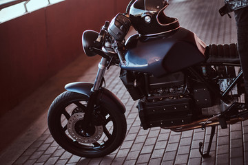 Cropped photo of a custom-made retro motorcycle on a footway under bridge.