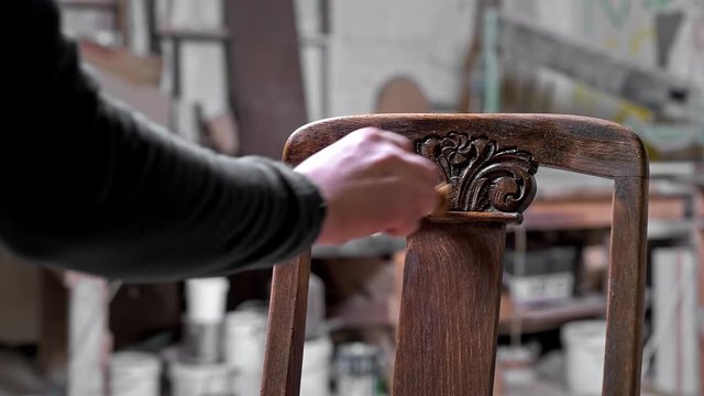 Man hand painting a wooden old chair