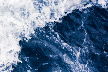 Beautiful blue sea diagonal wave with white foam and bubbles during high tide, close up