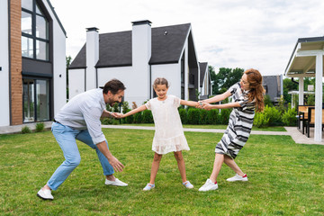 Obraz premium Young daughter. Pleasant cute girl standing between her parents while spending time with her family