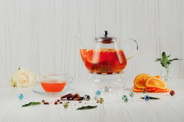 Fruit tea from oranges on a white background, next to an orange, chocolate, glass balls