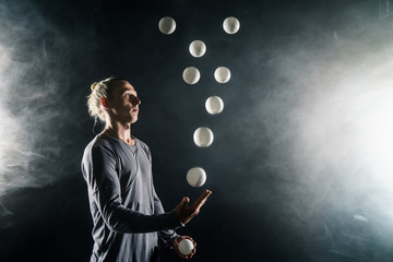 Blond juggler with white balls on black background - obrazy, fototapety, plakaty