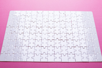 White puzzle on pink background. Top view