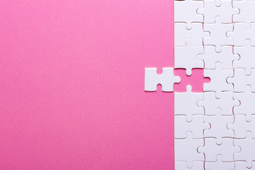 White puzzle on pink background. Top view