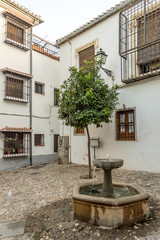 Fototapeta na wymiar A small fountain and a tangerine tree in the moorish neighbourhood in Granada, Spain