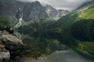 Beautiful view of green forest, hills and rocky mountains with reflection on the Morskie Oko lake, High Tatras, Zakopane, Poland. Foggy day