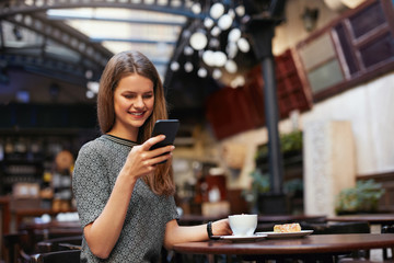 Woman With Mobile Phone In Cafe