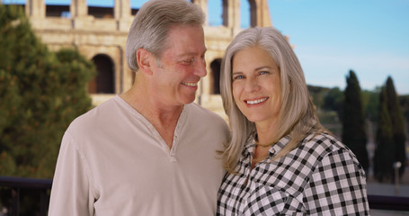 Happy mature Caucasian couple smile happily in front of Colosseum in Rome