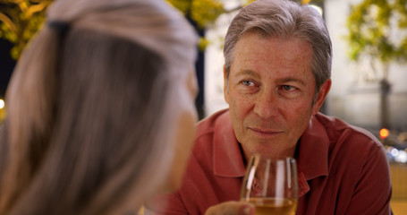 Mature Caucasian male chats with female at restaurant over wine