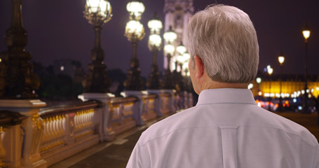 Obraz premium Old white man travelling Paris looks around city on Pont Alexandre bridge
