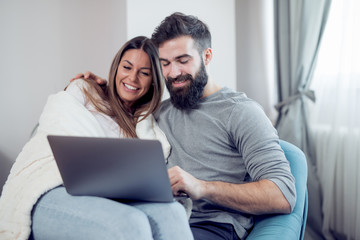 Young couple relaxing on sofa with laptop in the living room