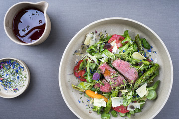 Modern spring salad with barbecue dry aged sliced fillet steak and green asparagus as top view on a...