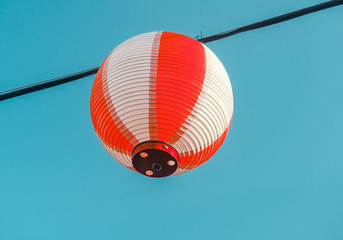 Obraz premium Paper red-white japanese lanterns Chochin hanging on blue sky background