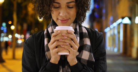 Close up of pretty African female holding coffee cup on Champs-Elysees street