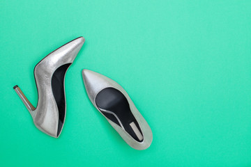 Fashion blog concept. bright silver women high heel shoes on mint green background. Flat lay, top view trendy beauty female background.