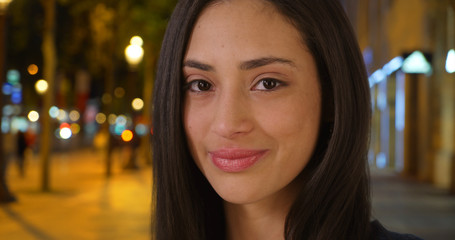 Beautiful Latina female stands on Champs Elysees avenue smiling at camera
