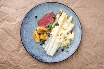Modern Style gegrilltes Rinderfilet Steak aufgeschnitten mit weißen Spargel und Bratkartoffel in Hollandaise Sauce als Draufsicht auf einem Teller