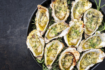 Barbecue overbaked fresh opened oyster with garlic and herbs offered as top view on a tray with...