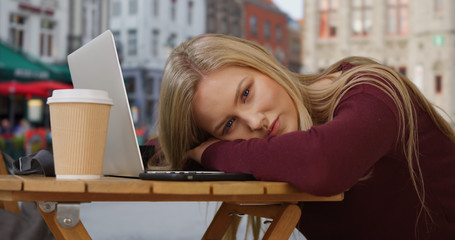 Beautiful white girl in Bruges stares deeply at camera while resting her head