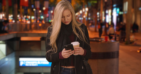 Blonde Caucasian woman lost in Paris looks up directions at Champs-Elysees