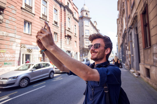 Cheerful guy take selfie with smartphone on the street