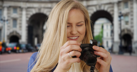 Traveling young white woman takes pictures near Admiralty Arch in London