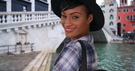 Beautiful African-American woman near Rialto Bridge in Venice poses happily