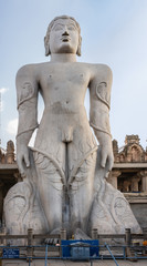 Obraz premium Shravanabelagola, Karnataka, India - November 1, 2013: At the Jain Tirth, gray granite Giant Bhagwan Bahubali statue. Temple building and sky in back.