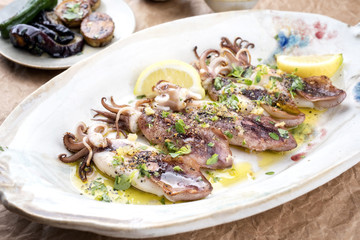 Traditional barbecue Greek calamari with herb and lemon as top view on a plate