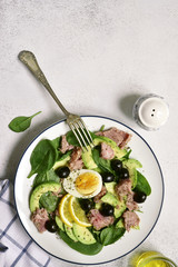 Avocado spinach salad with tuna, boiled eggs and olive oil.Top view.