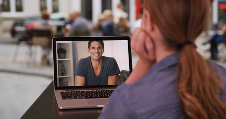 Young Caucasian woman having video conversation with white man outside on laptop
