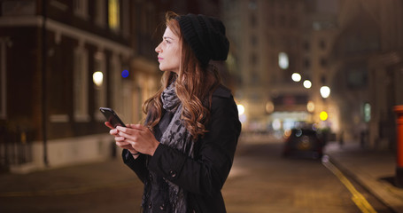 Millennial Caucasian female looking for friend sending text outside in street