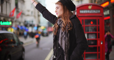 Attractive Caucasian female calling for taxi cab in London street