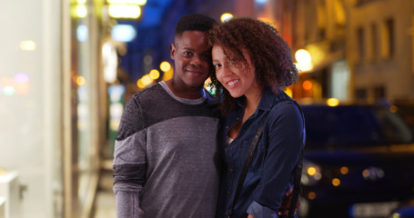 Happy African American couple pose for a portrait in the city at night