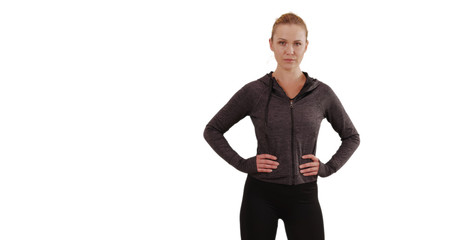 Stern blonde young lady on white background posing proudly with hands at hips