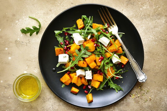 Delicious autumn pumpkin salad with arugula, feta cheese and pomegranate seeds.Top view.