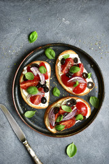 Toasts with soft cheese, cherry tomato, red onion and black olives.Top view with copy space.