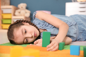 Little autistic girl playing with cubes at home