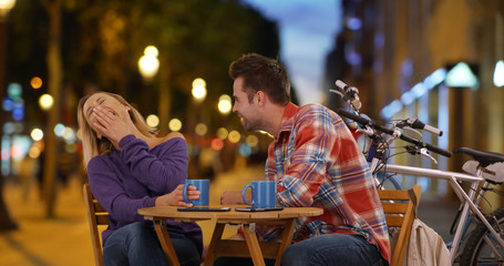Smiling couple having coffee on the Champs-Elysees at night