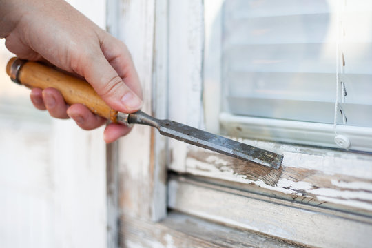 hand removing glazing putty with a chisel